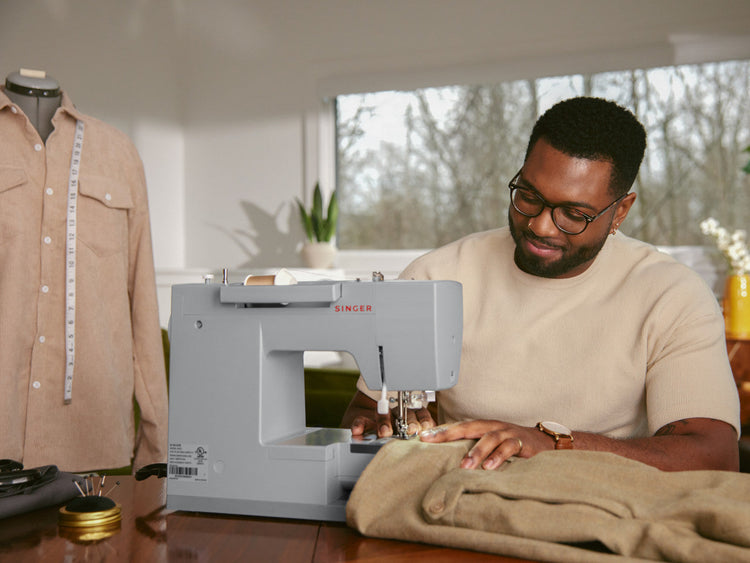 A man sews a garment with thick fabric with a Singer Heavy Duty sewing machine