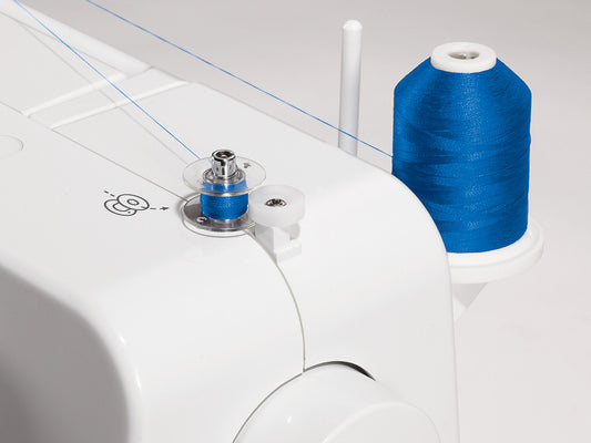 Close up of a bobbin winding royal blue thread on a SINGER 1409 Promise sewing machine