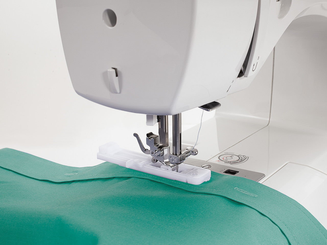 A close up of a SINGER Talent 3321 sewing machine stitching a buttonhole on a jade green shirt