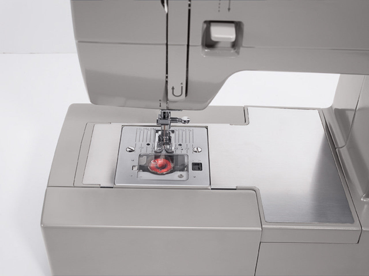 Close up of a top-drop bobbin on a SINGER heavy duty 4423 sewing machine with red thread on the bobbin.