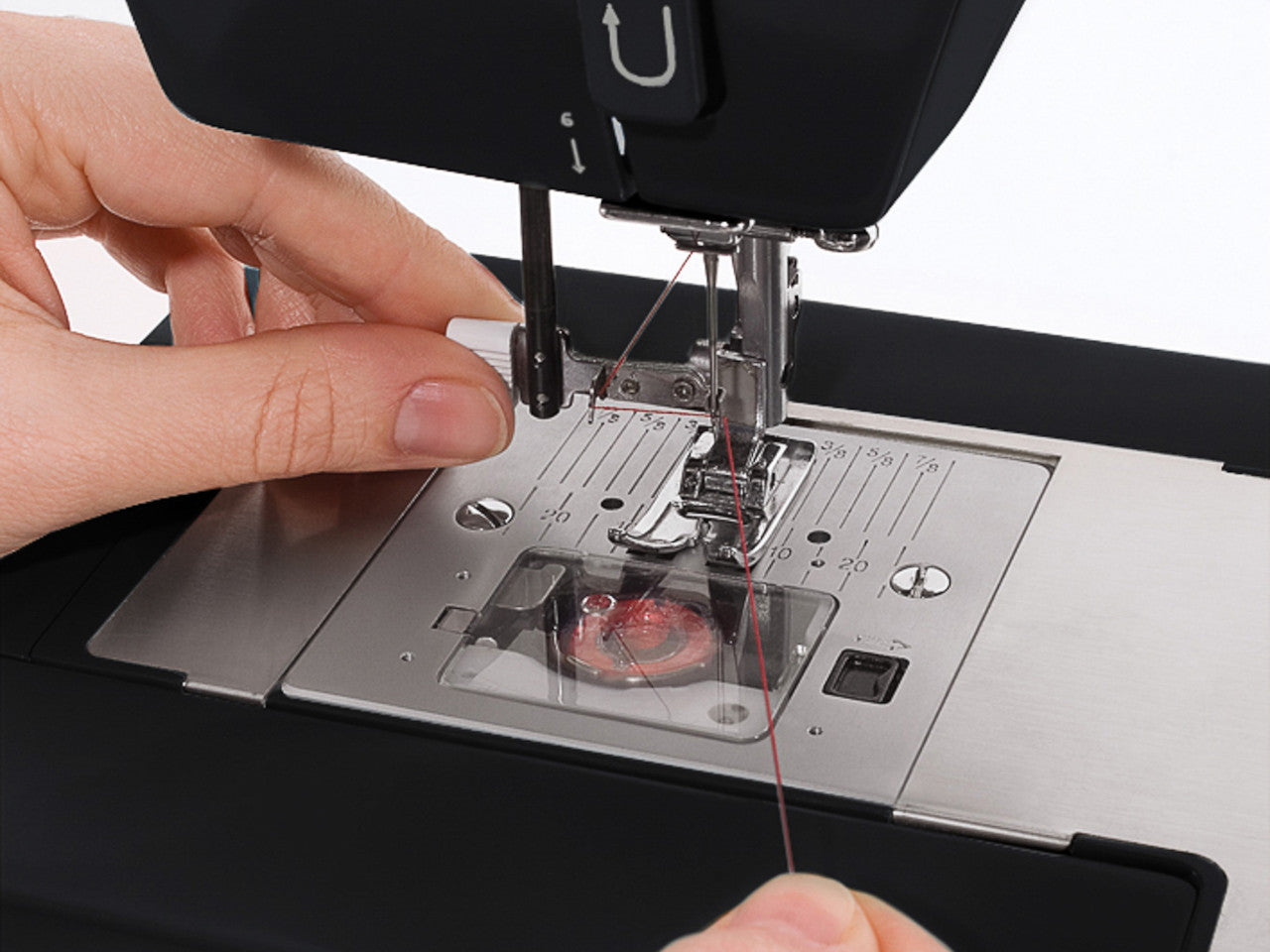 Close up of threading a needle on the SINGER HD4432 heavy dutysewing machine with black needle threader