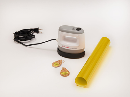 A product shot of the Singer Momento Mini Press with an electric cord and plug, with two hand made earings in a teardrop shape and a roll of yellow vinyl.